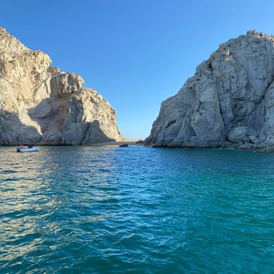 Dramatic white rock formations rising from turquoise water with a small boat in the channel