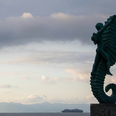 Bronze seahorse sculpture on the Puerto Vallarta Malecón at dusk with the bay behind
