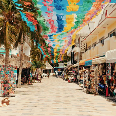 Sayulita market street strung with colorful papel picado flags, shops and palm trees